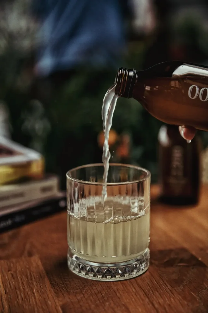 Alcohol-free drink being poured into a clear glass with ice.
